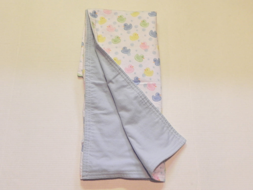 Pastel baby duck print baby blanket showing blue flannel backing