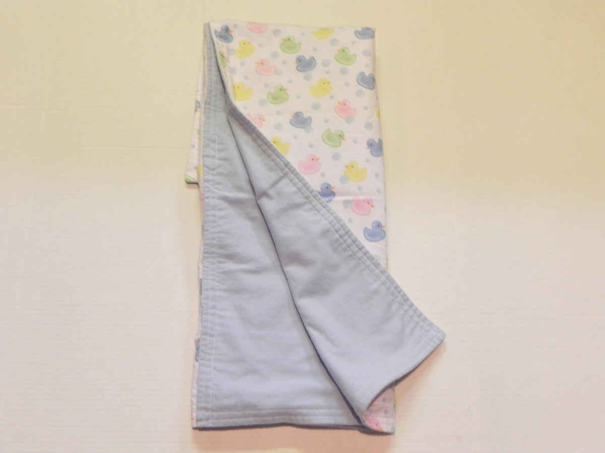Pastel baby duck print baby blanket showing blue flannel backing